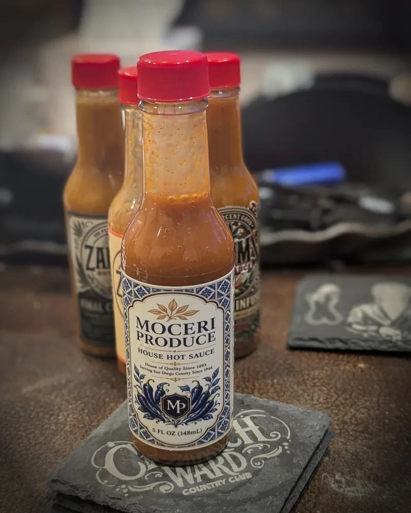 A Moceri Produce house hot sauce bottle on slate coasters