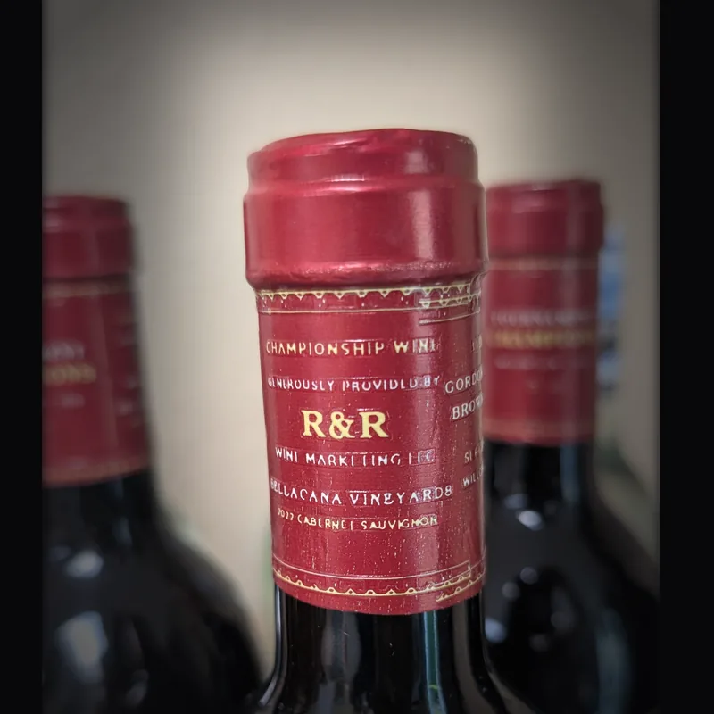 Close-up of a custom red neck capsule on a Tournament Champions bottle