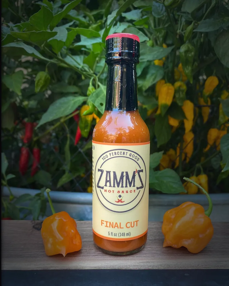 A bottle of Zamm'Z Final Cut hot sauce among peppers
