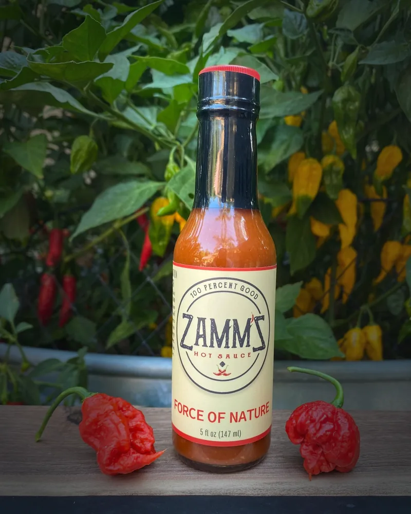 A bottle of Zamm'Z Force of Nature hot sauce among peppers