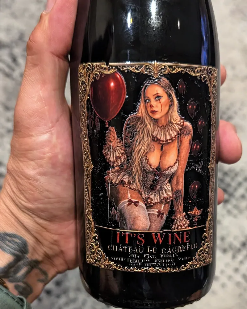 A custom red front label on a bottle, held in a hand