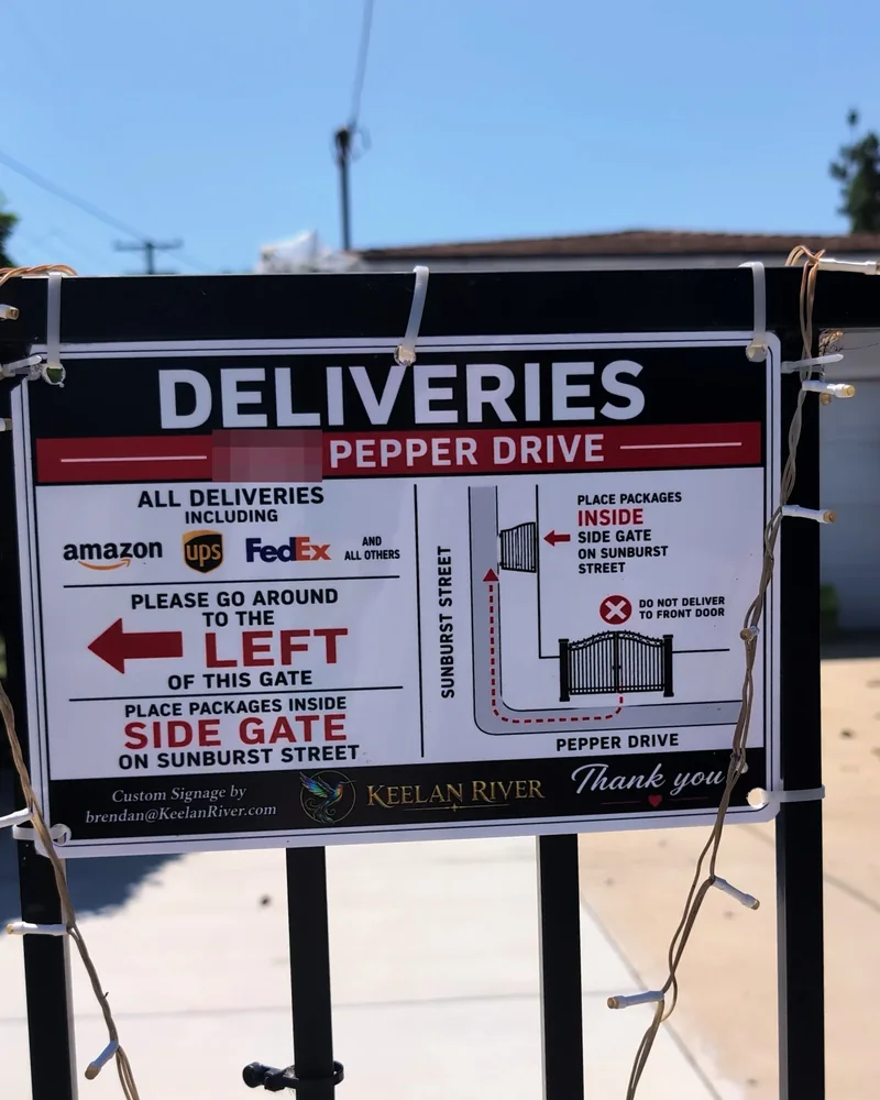 Custom deliveries sign on a gate directing packages to the side gate (house number blurred)