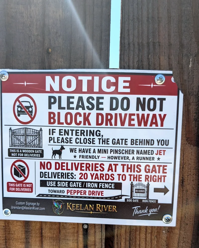 Custom notice sign reading Please Do Not Block Driveway, installed on a wood fence